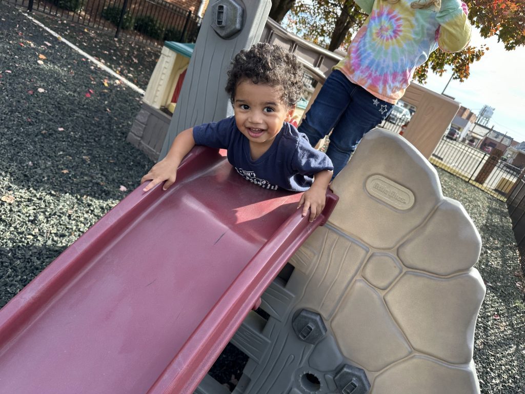 A child smiles from the top of the slide.