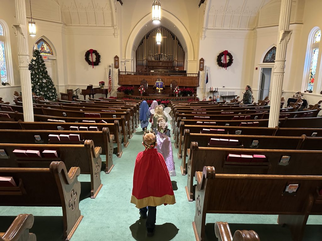 Children proceed to the front of a church during practice for a Christmas program.