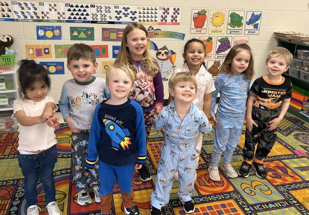 Children pose for a photo in the three-year-old classroom.